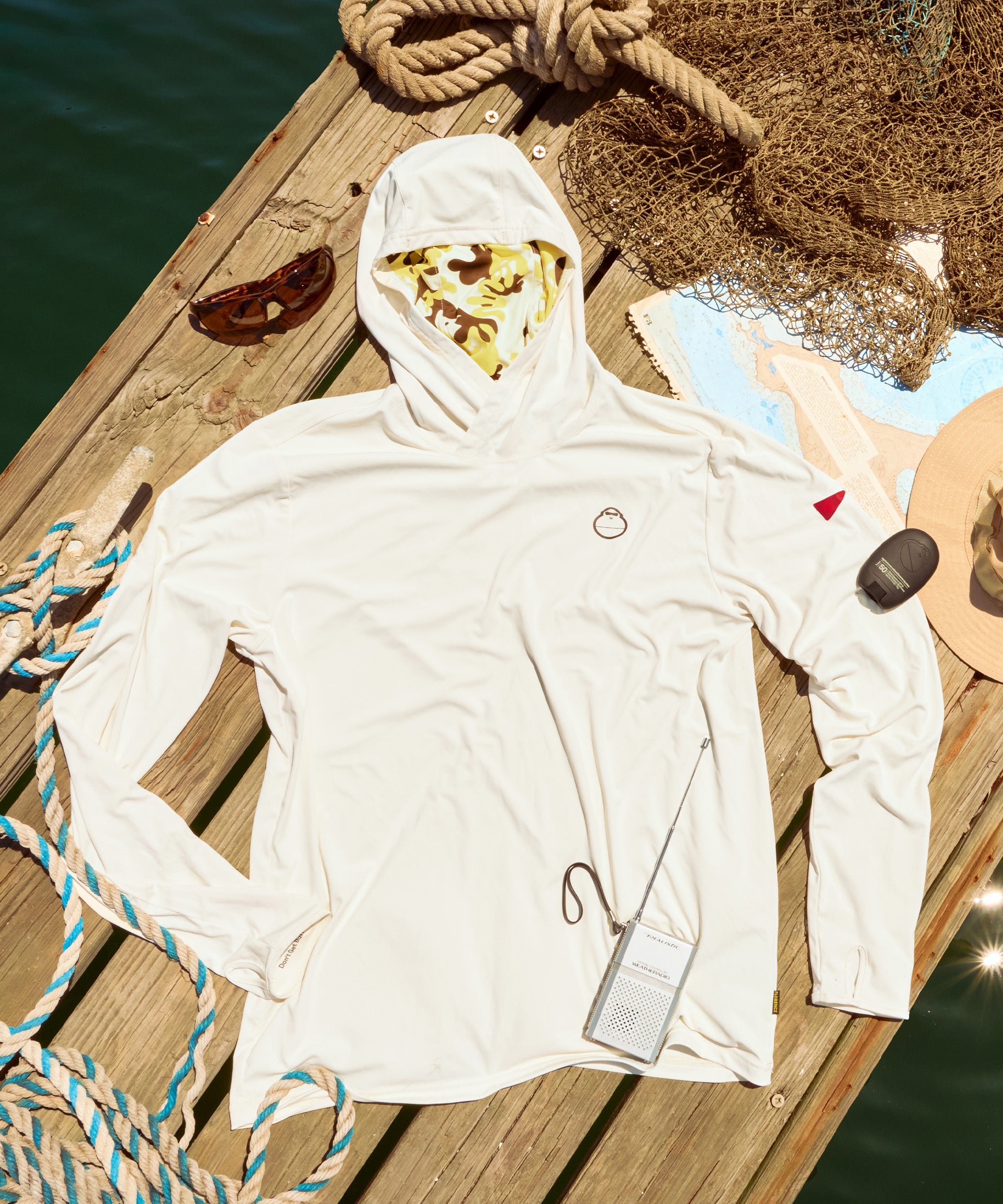 White hoodie with a face mask on a wooden dock by the water