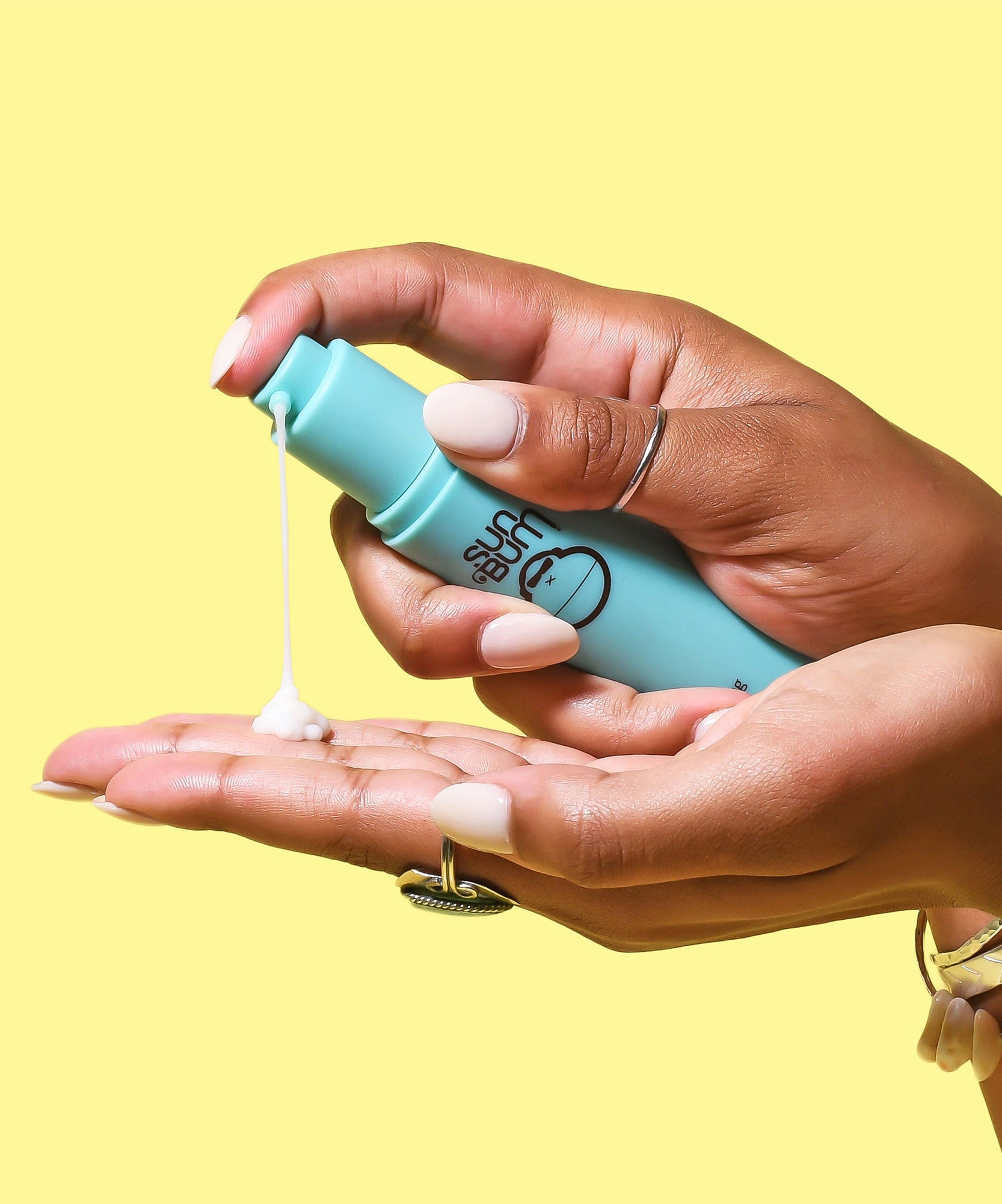 Hands dispensing hydrating serum from a blue Sun Bum bottle.