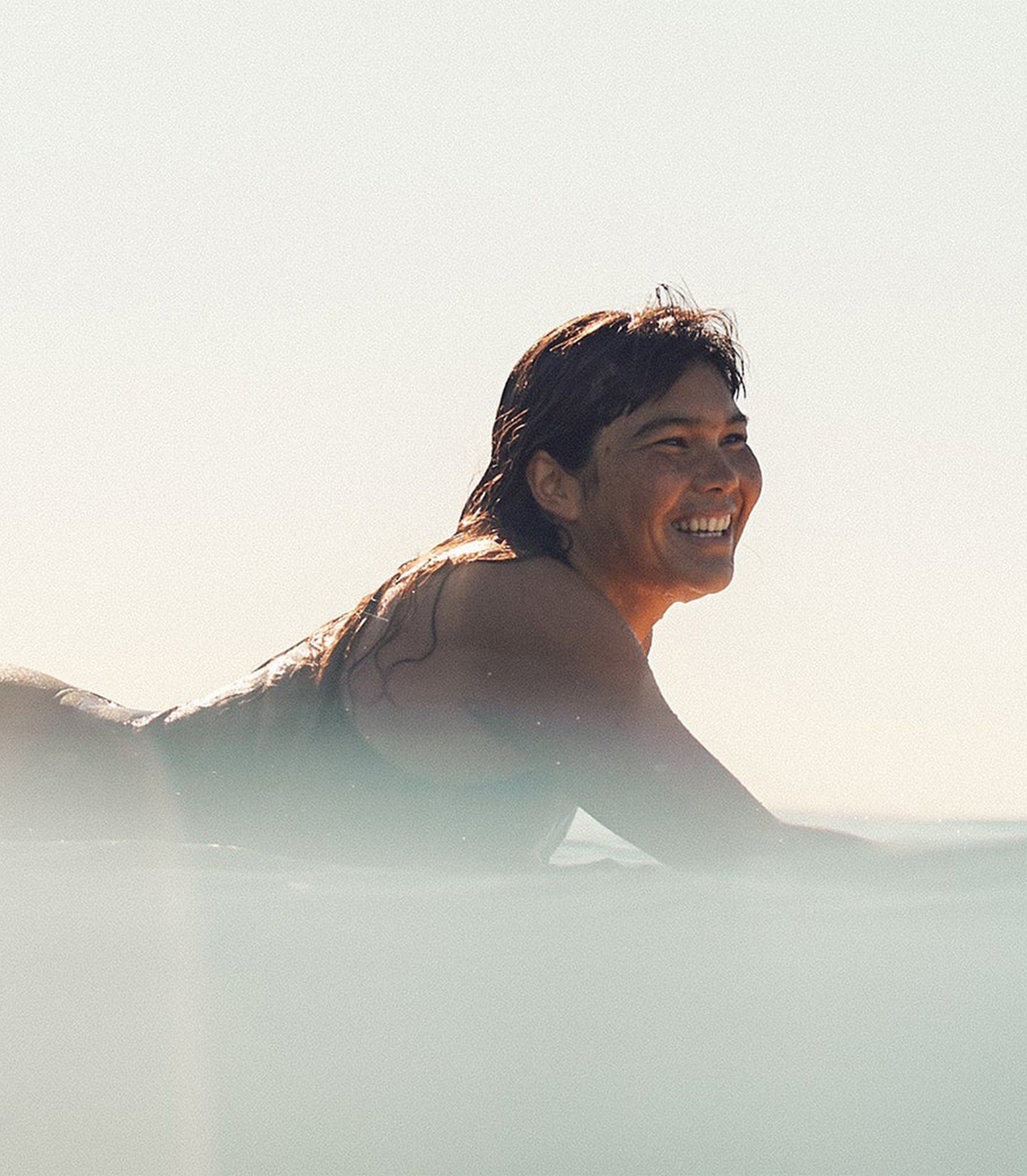 Person with wet hair smiling outdoors on a bright day