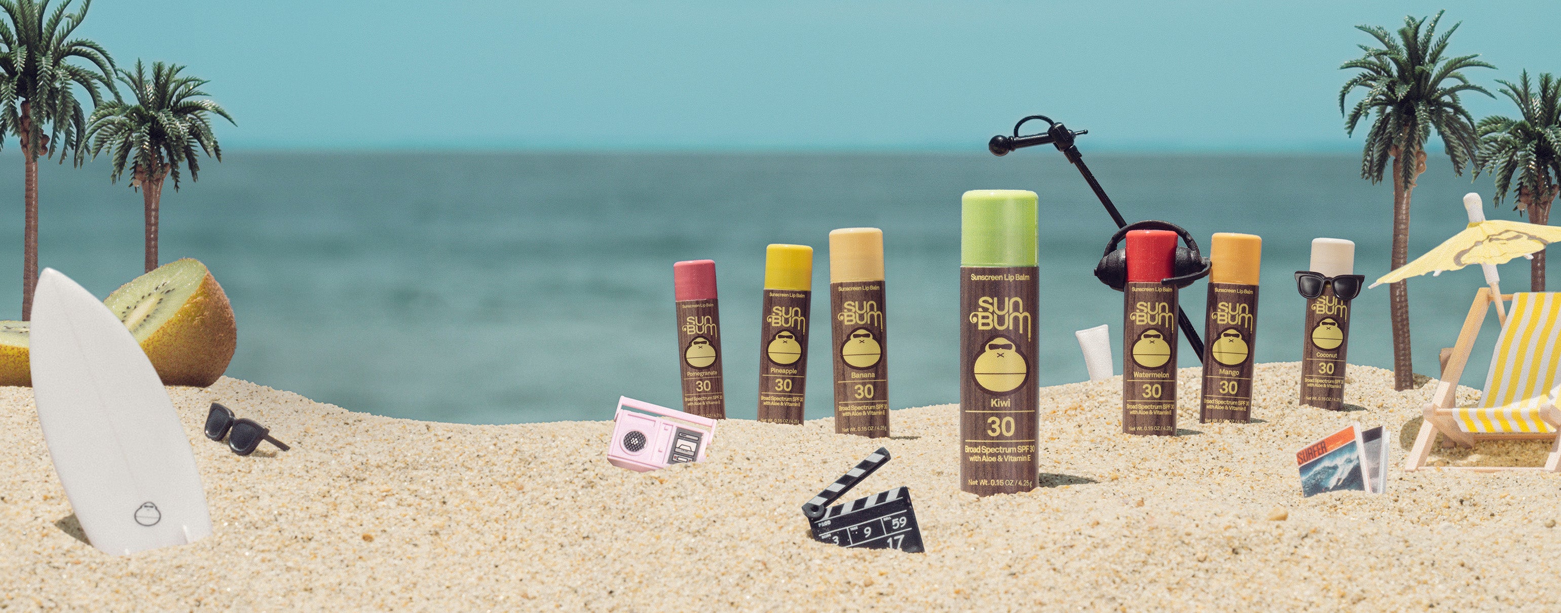 Colorful SPF 30 lip balms in fruity flavors chill on the beach in a fun scene – Lip Collection - Sun Bum.