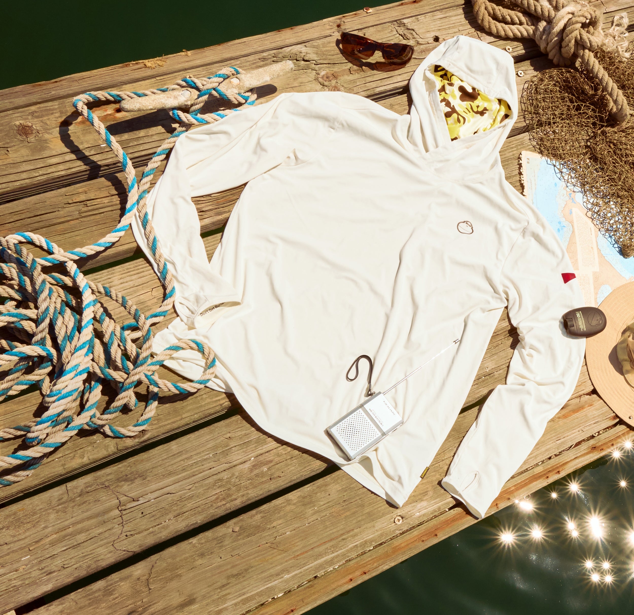 White hoodie on a wooden surface with ropes and sunglasses