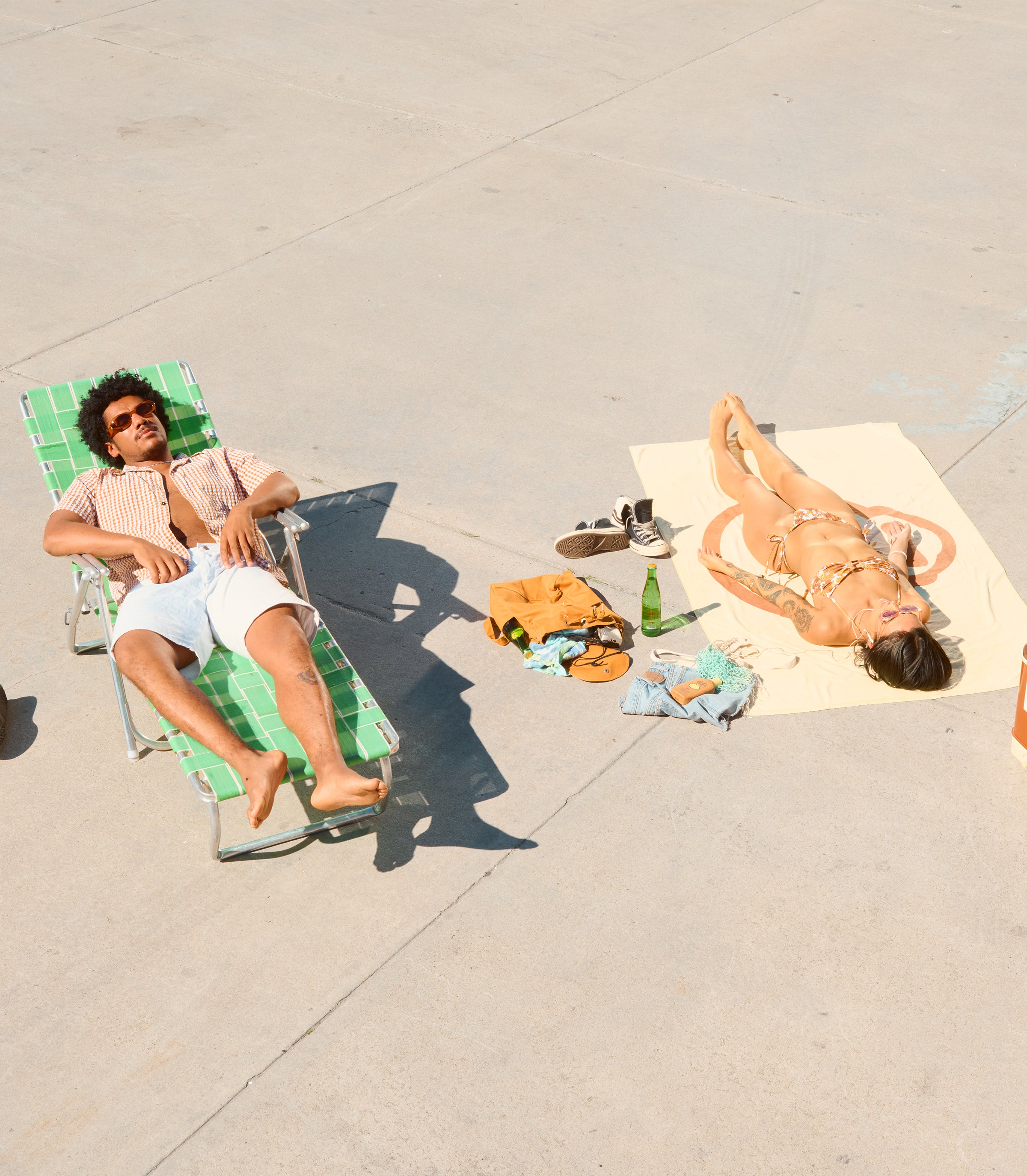 Two friends sunbathing on pavement with laid-back vibes and essentials nearby – Bestsellers Collection - Sun Bum