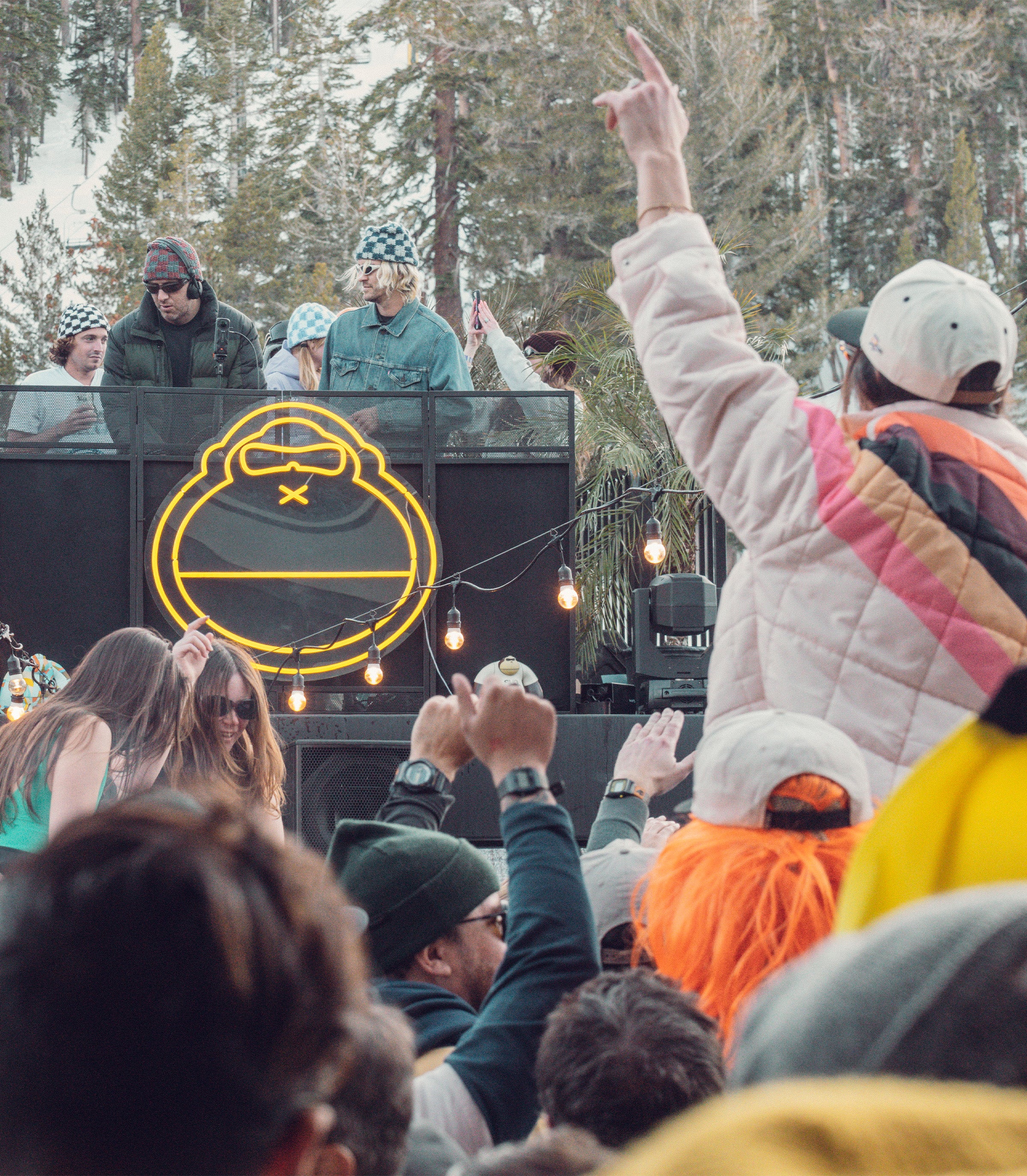 Crowd dancing at outdoor DJ set with neon Sun Bum logo glowing in the background – Community Discounts - Sun Bum.