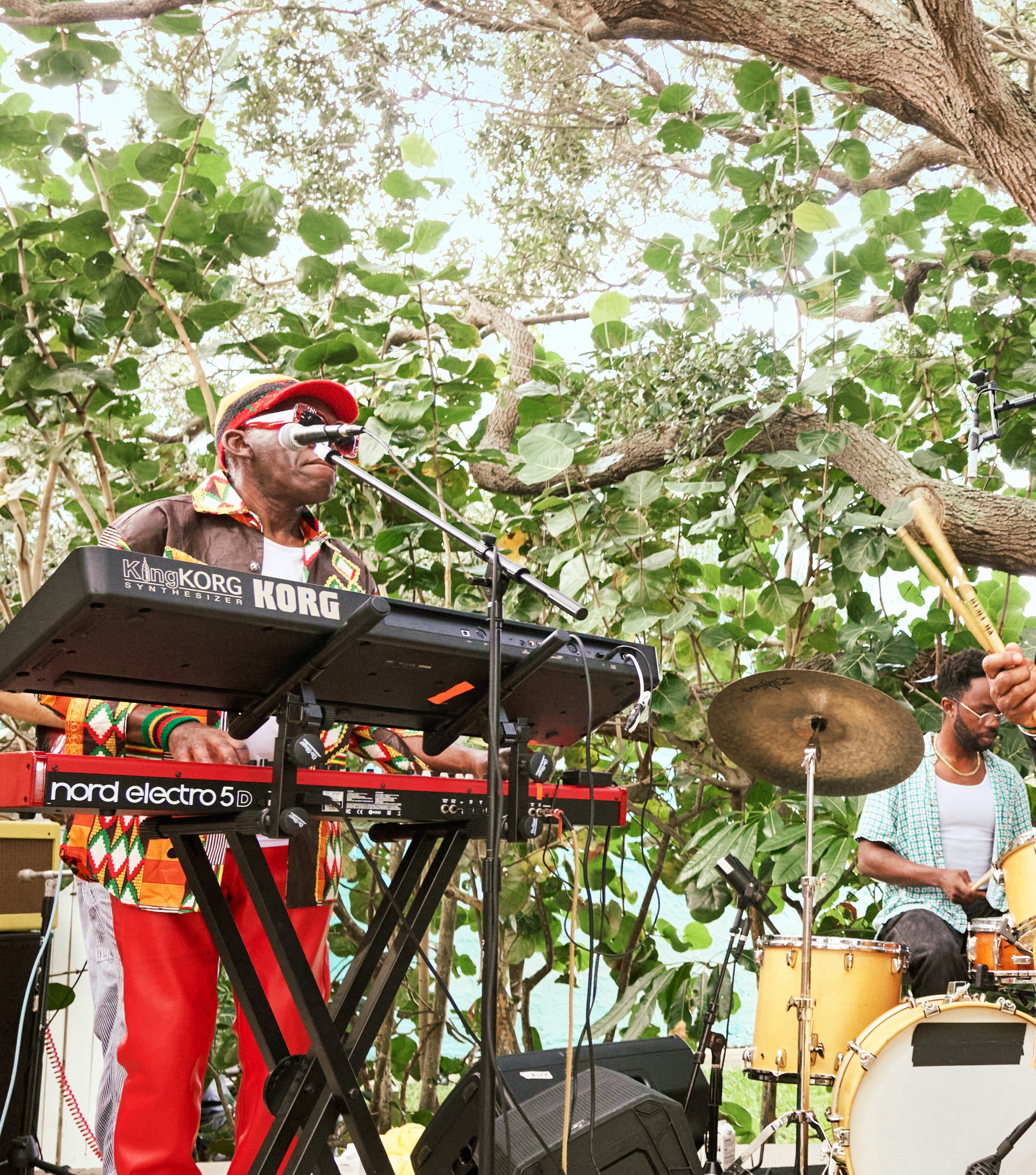 Live band plays reggae under lush trees at Sonny's Porch with keyboards, drums, and good vibes – Discover Collection - Sun Bum.
