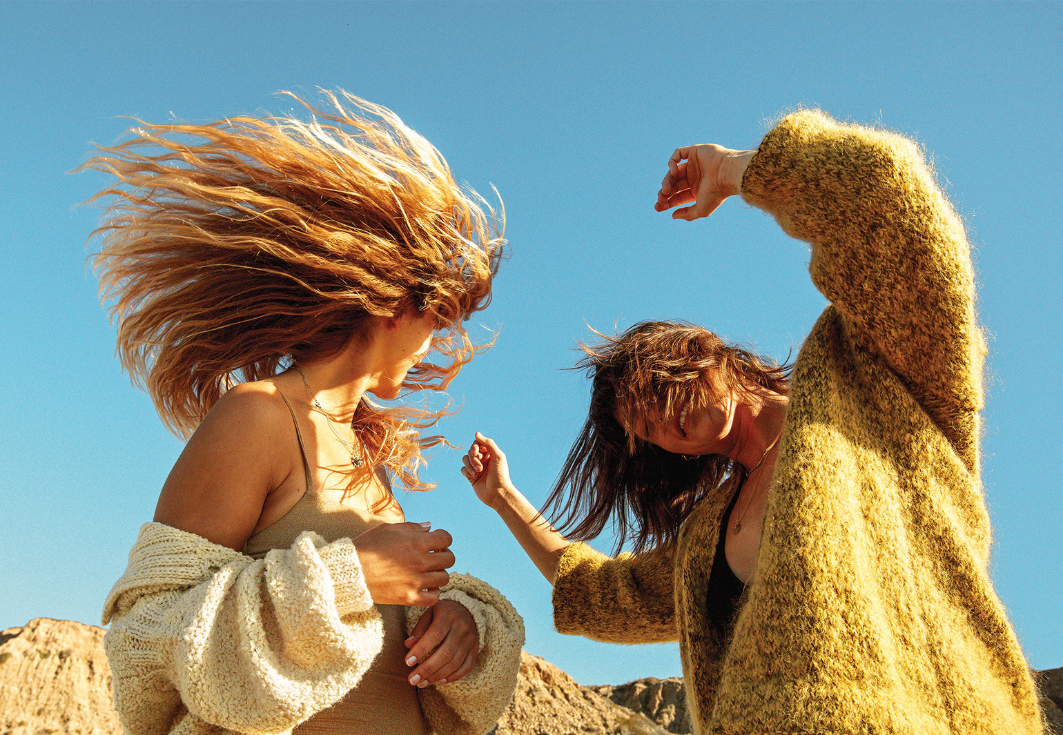 Two girls dancing in the wind with their beachy hair looking fun and free. - Sun Bum
