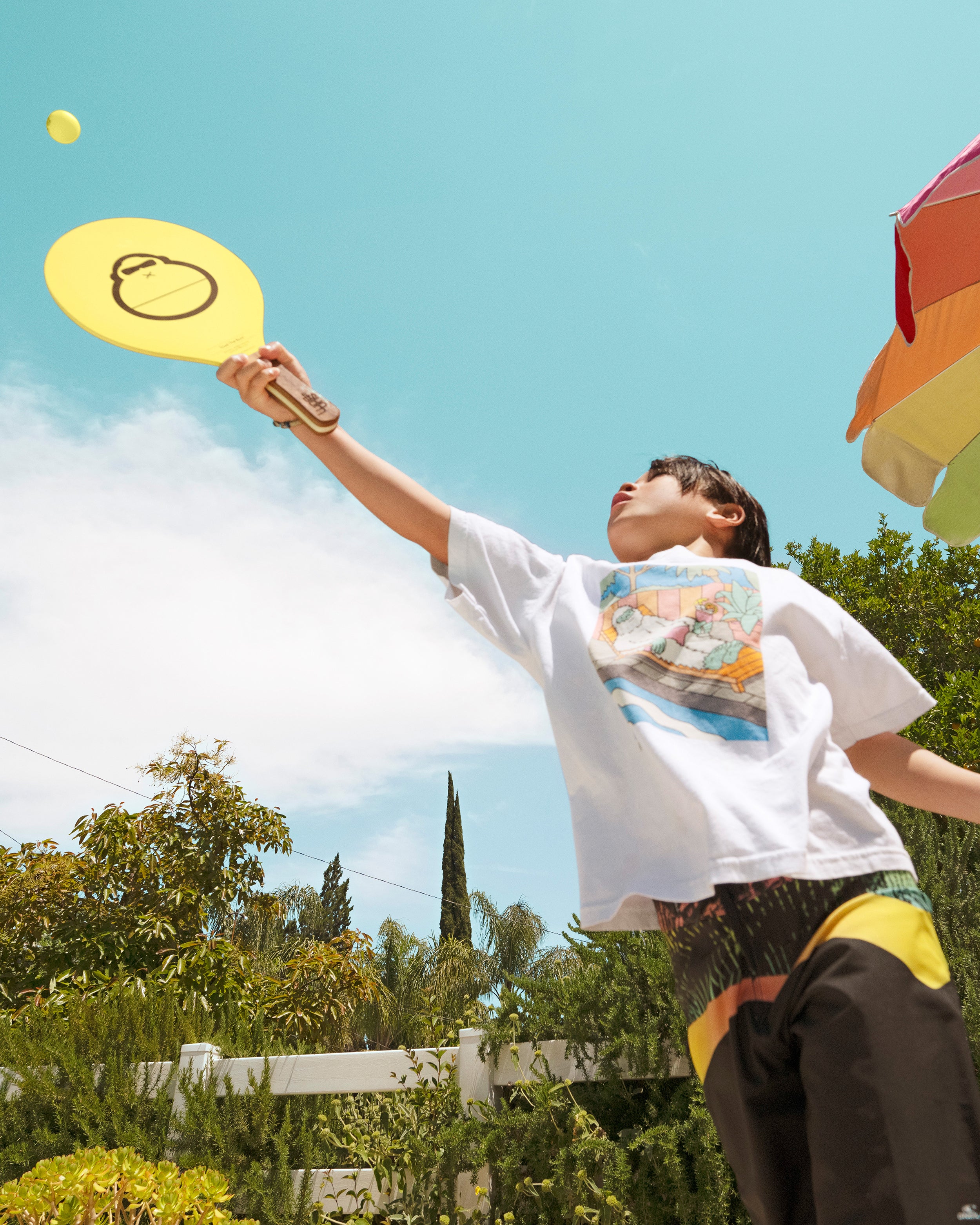 Boy playing paddleball with Sun Bum paddle ball set