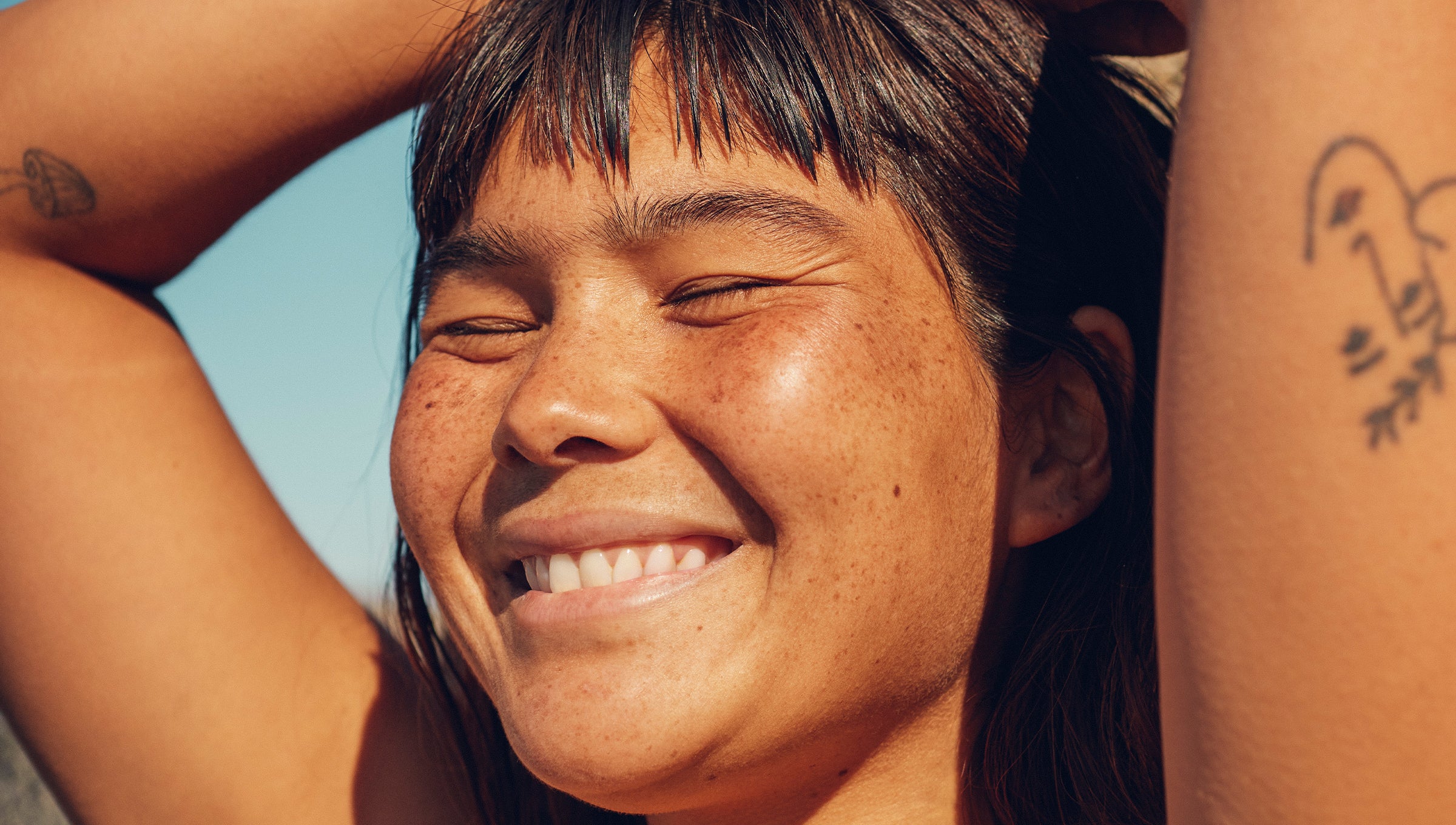 Close-up of a smiling woman enjoying the sun, promoting skin self-check awareness from the Know Your Spots Collection - Sun Bum.