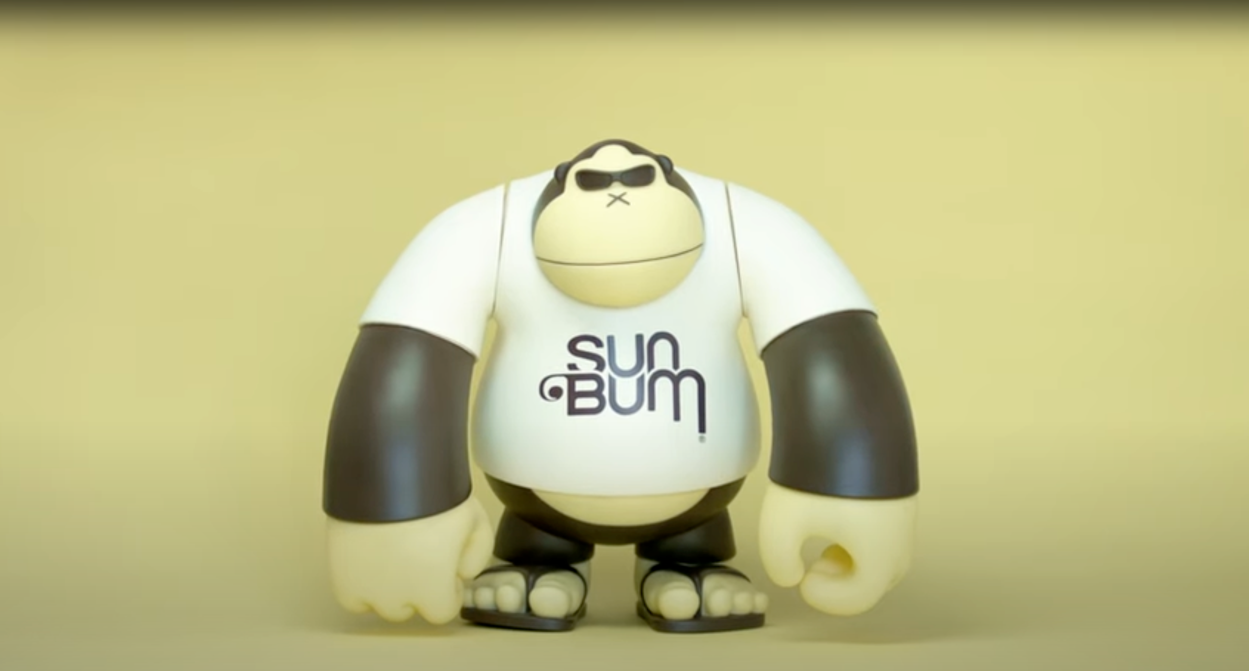 Toy figure wearing a 'Sun Bum' t-shirt on a beige background